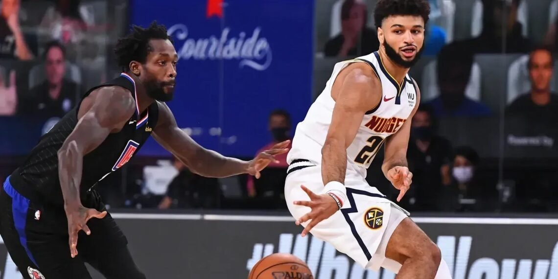 Jogador dos Nuggets dribla adversário dos Clippers em uma intensa partida de basquete, destacando habilidades e competição.