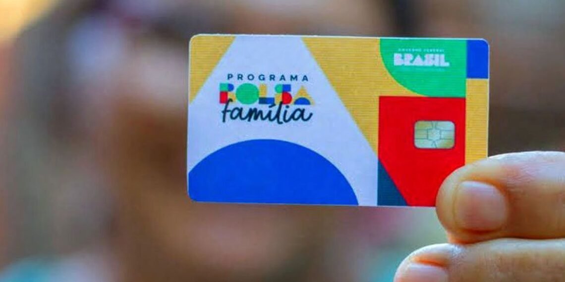 Cartão do Programa Bolsa Família sendo segurado por uma mão, destacando cores vibrantes e chip de segurança.