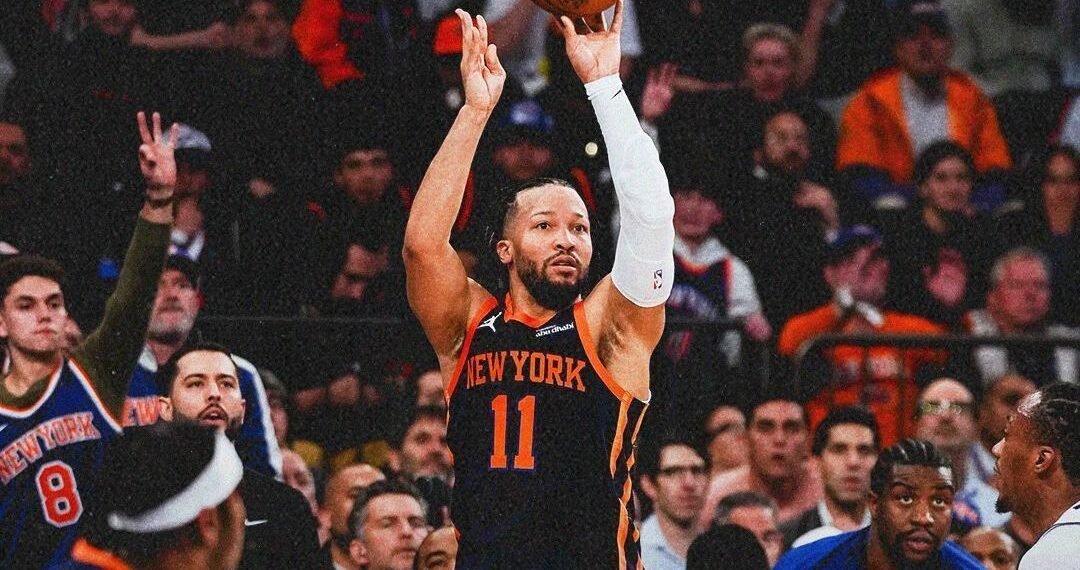 Jogador do New York Knicks arremessa bola enquanto a torcida observa empolgada durante partida de basquete da NBA.