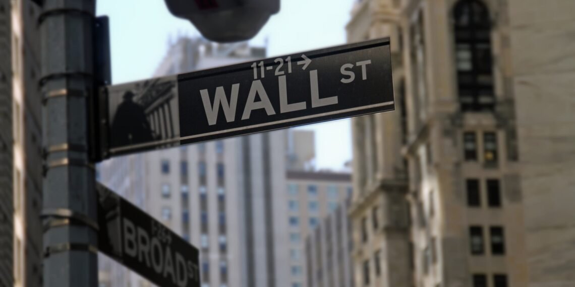 Placa de rua de Wall Street em Nova York, cercada por edifícios altos, simbolizando o centro financeiro global.