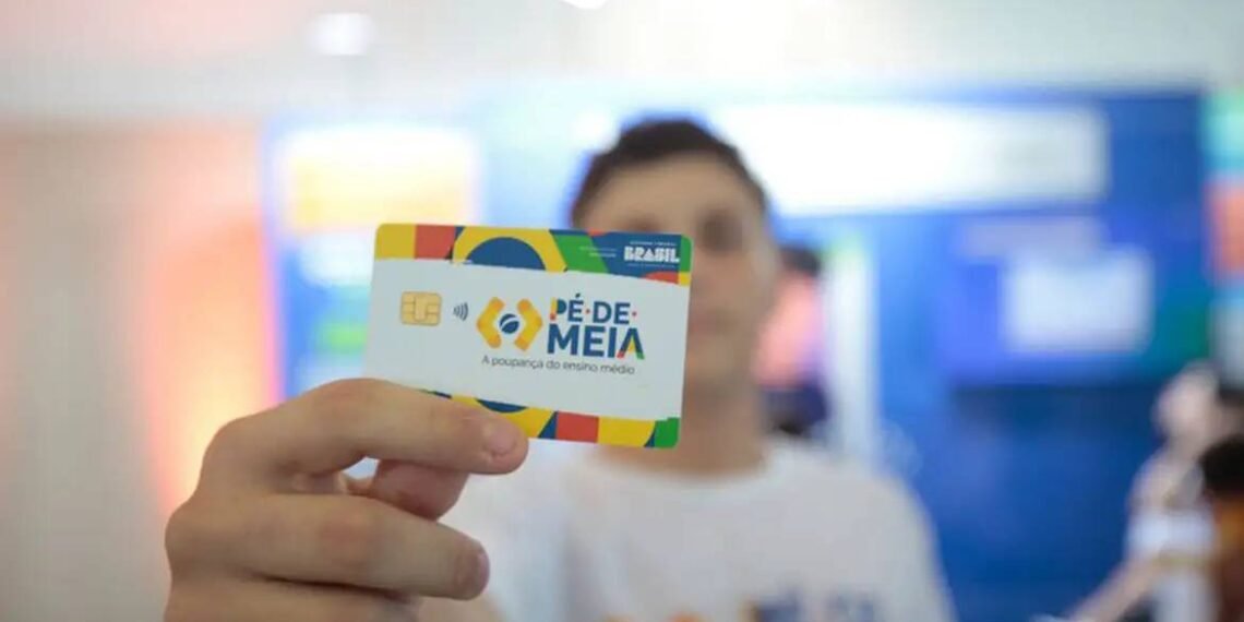 Pessoa segura um cartão Pé-de-Meia, destacando a iniciativa de poupança para estudantes do ensino médio no Brasil.