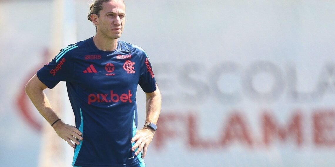 Treinador do Flamengo observa o treino vestindo uniforme do clube, destacando concentração e foco no ambiente esportivo.