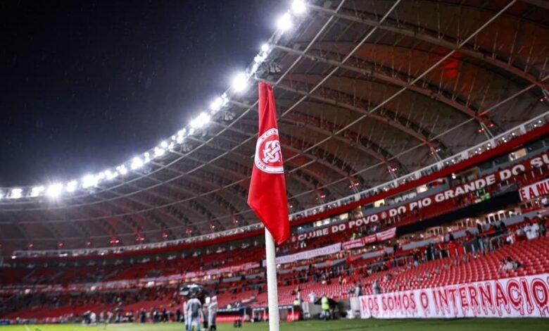 Estádio lotado de torcedores do Internacional, com banners de promoções especiais para o jogo contra o Corinthians, destacando ações de marketing para atrair mais fãs.