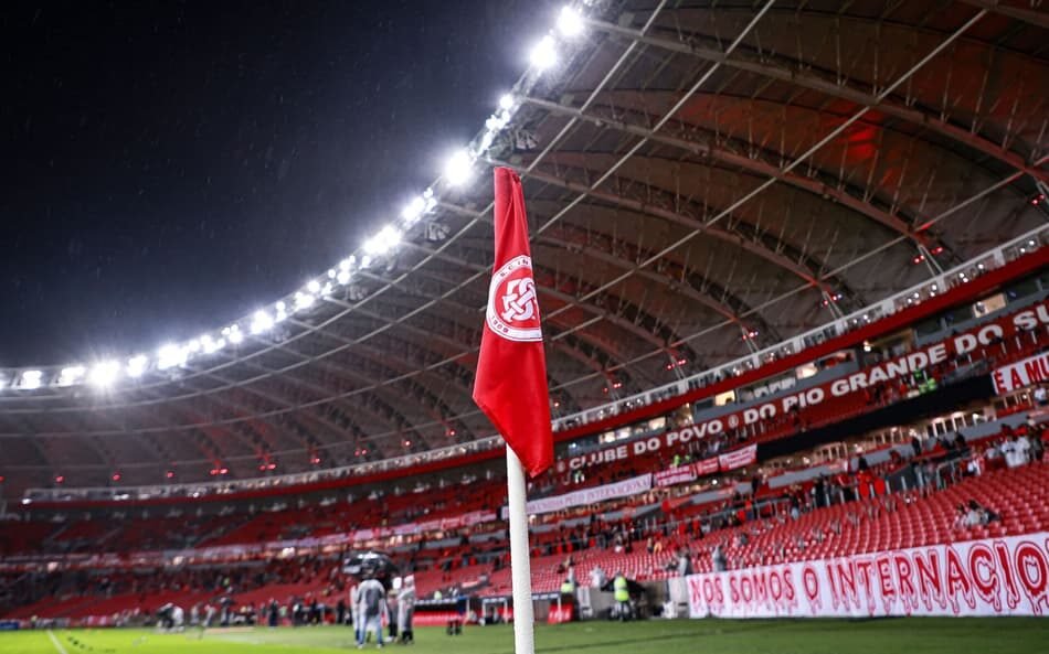 Estádio lotado de torcedores do Internacional, com banners de promoções especiais para o jogo contra o Corinthians, destacando ações de marketing para atrair mais fãs.