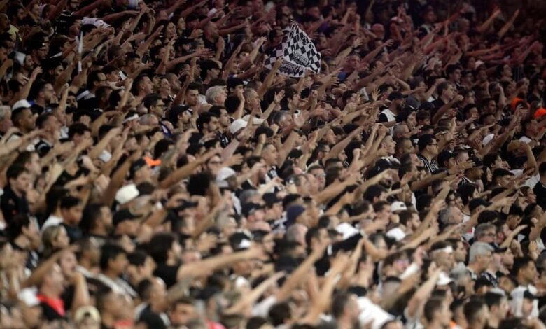 Torcida organizada do Corinthians celebra retorno aos estádios após liberação judicial, destacando bandeiras e entusiasmo dos torcedores.