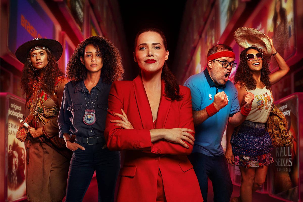 Cinco pessoas em pé em uma rua iluminada à noite. No centro, mulher de terno vermelho com braços cruzados. Ao redor, pessoas com roupas casuais e estilos variados. Texto