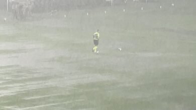 Chuva interrompe partida de futebol entre Vasco e Internacional no estádio São Januário, com campo encharcado e jogadores aguardando retomada do jogo.