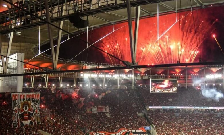 Festa no Maracanã com torcedores e jogadores do Flamengo celebrando o tetracampeonato da Copa Libertadores da América, com fogos de artifício iluminando o estádio emblemático do Rio de Janeiro.