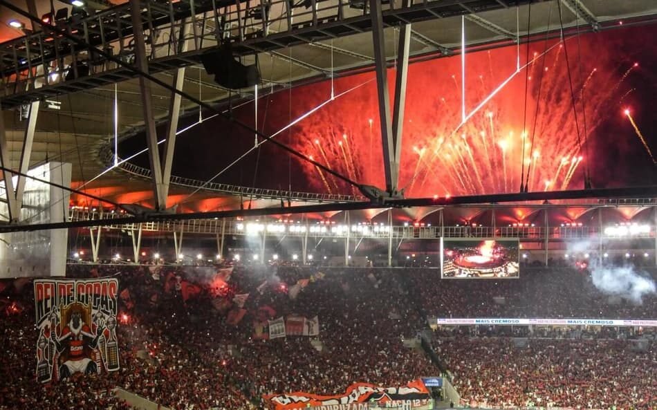 Festa no Maracanã com torcedores e jogadores do Flamengo celebrando o tetracampeonato da Copa Libertadores da América, com fogos de artifício iluminando o estádio emblemático do Rio de Janeiro.