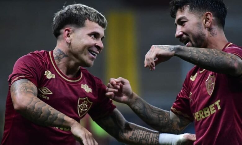 Jogadores do Fluminense fazem a famosa comemoração de Bruno Henrique e Gabigol, estrelas do Flamengo, em uma partida de futebol, mostrando integração esportiva e rivalidade saudável.