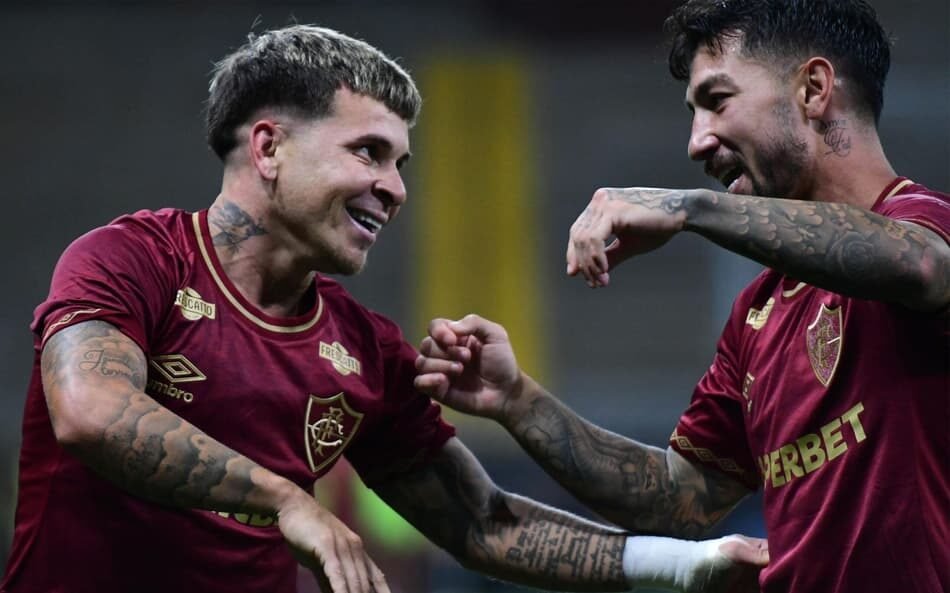 Jogadores do Fluminense fazem a famosa comemoração de Bruno Henrique e Gabigol, estrelas do Flamengo, em uma partida de futebol, mostrando integração esportiva e rivalidade saudável.