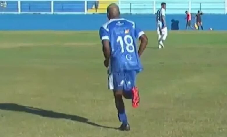 Jogador do Goytacaz em campo usando tornozeleira eletrônica, destaca-se em meio à repercussão internacional sobre sua participação em partidas de futebol.