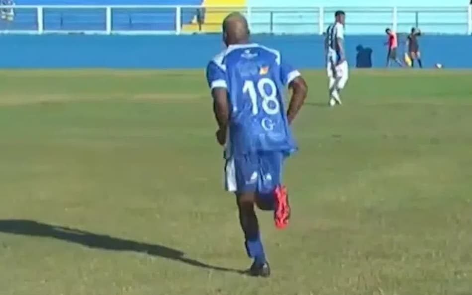 Jogador do Goytacaz em campo usando tornozeleira eletrônica, destaca-se em meio à repercussão internacional sobre sua participação em partidas de futebol.