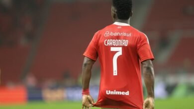 Fotografia de Johan Carbonero com a camisa do Internacional, após ser adquirido pelo clube em uma transação milionária, destacando seu entusiasmo em um estádio de futebol.