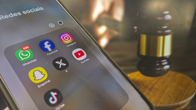 Imagem de um martelo de juiz ao lado dos logotipos da Meta e do YouTube simbolizando seu julgamento inédito sobre o impacto do design de aplicativos e vício em redes sociais.