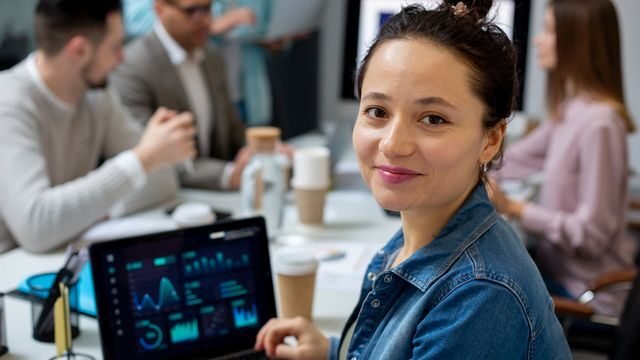 Um grupo de profissionais de tecnologia discutindo o impacto da inteligência artificial na carreira em TI, destacando habilidades essenciais para o futuro em um ambiente de trabalho moderno.